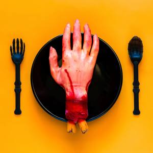 Image of a fake Halloween hand on a black plate with a fork and spoon to either side.