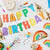 Flat lay image of colourful Happy Birthday themed party supplies with a Happy Birthday bunting.