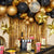 Image of a Hollywood themed party set up with a mix of gold and back balloons, a gold fringed wall decoration, hanging star decorations, Hollywood plates, popcorn boxes and decorative Oscar style trophies.