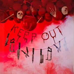 Image of a hanging Keep Out Halloween sign with skulls and balloons above and bloody weapons hanging below.